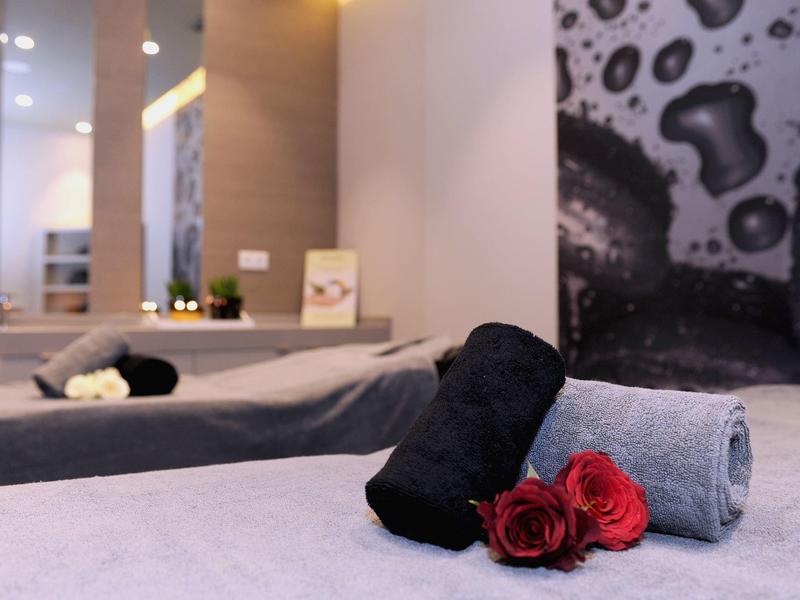 Elegantní wellness lůžko s ručníky a červenými růžemi v uvolněné hotelové atmosféře.