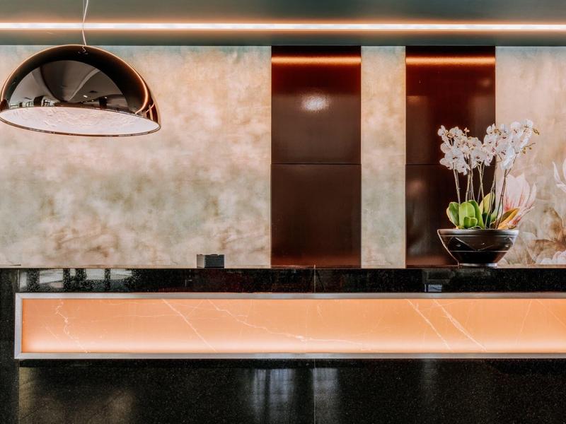 Moderní hotelová recepce s nepřímým osvětlením a květinovou dekorací.