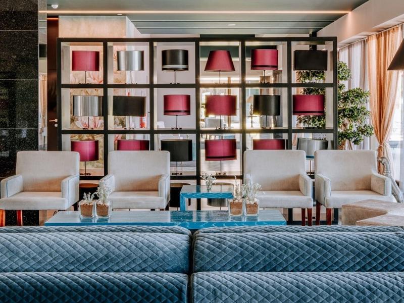 Moderní hotelová lounge s křesly, pohovkou a dekorativními policemi v pozadí.