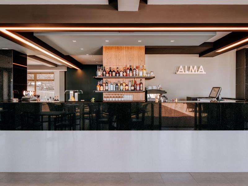 Moderní hotelový bar s elegantními dřevěnými regály a útulným osvětlením