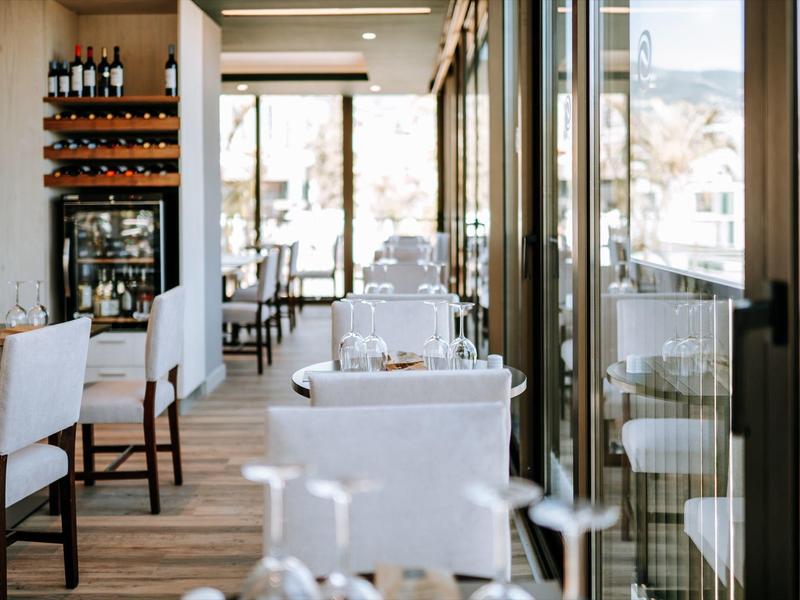 Elegantní restaurace s bílými židlemi a velkými okny s výhledem na hory