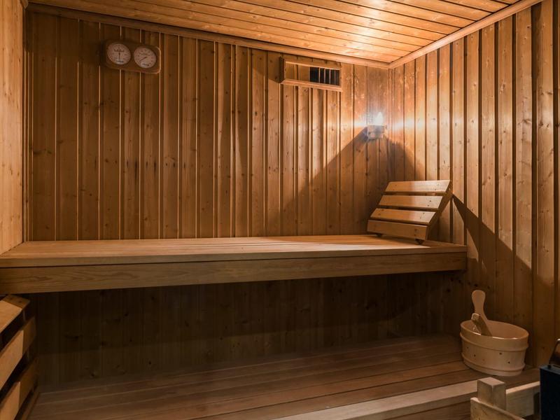 Jasná, útulná sauna s dřevěnými stěnami, lavičkou a tradičním saunovým vědrem.