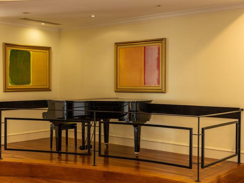 Černé piano na dřevěné podložce s moderním nástěnným uměním v hotelovém pokoji