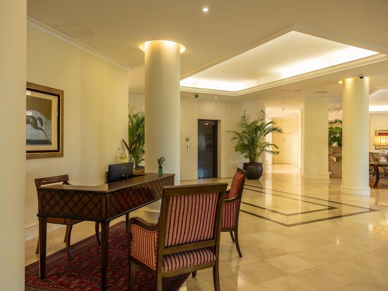 Světlá hotelová hala s stolem, židlemi a dekoracemi.