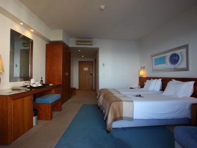 Modernes Hotelzimmer mit Doppelbett, Schreibtisch, Spiegel und indirekter Beleuchtung.