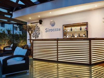 Modern beleuchtete Hotelbar mit Holztheke und gemütlichen Sitzgelegenheiten auf der Terrasse.