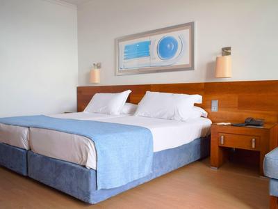 Zweibettzimmer mit blauen Bettdecken, Holzkopfteil und modernem Dekor.