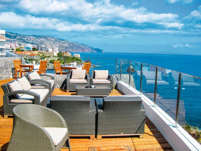 Moderne Außenterrasse mit Loungemöbeln und Blick auf das Meer und die Küste