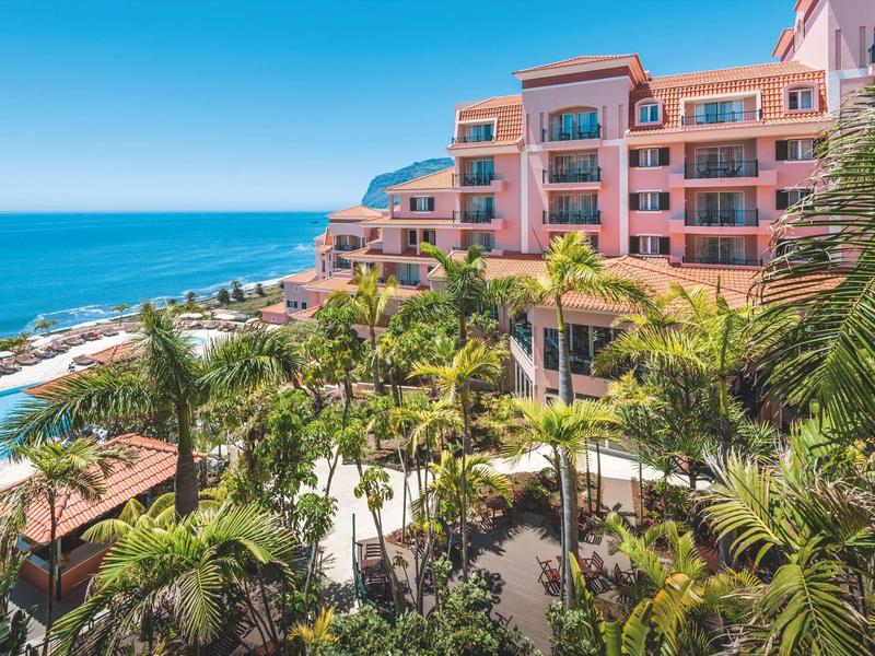 Resort di lusso sulla spiaggia con piscina, palme e vista sul mare blu