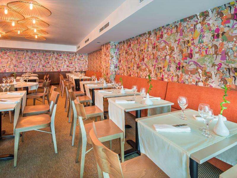 Ristorante moderno con murale colorato e tavoli apparecchiati in un hotel.