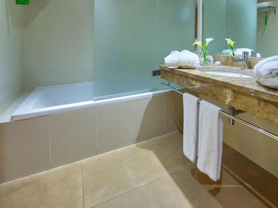 Baño luminoso con bañera, lavabo de madera y pared de vidrio esmerilado.