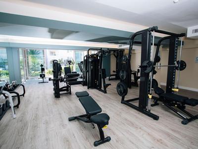 Moderner Fitnessraum mit Kraftgeräten und Hantelbänken in einem Hotel.