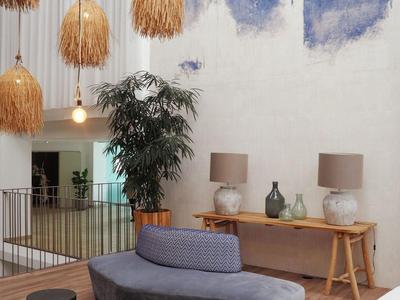 Interior moderno de hotel con sofá gris-azul, lámparas y luces colgantes en el techo.