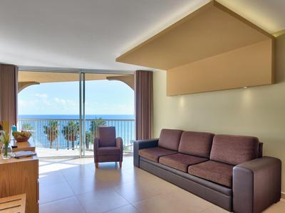 Modern eingerichtetes Wohnzimmer mit lila Sofa und Meerblick vom Balkon.