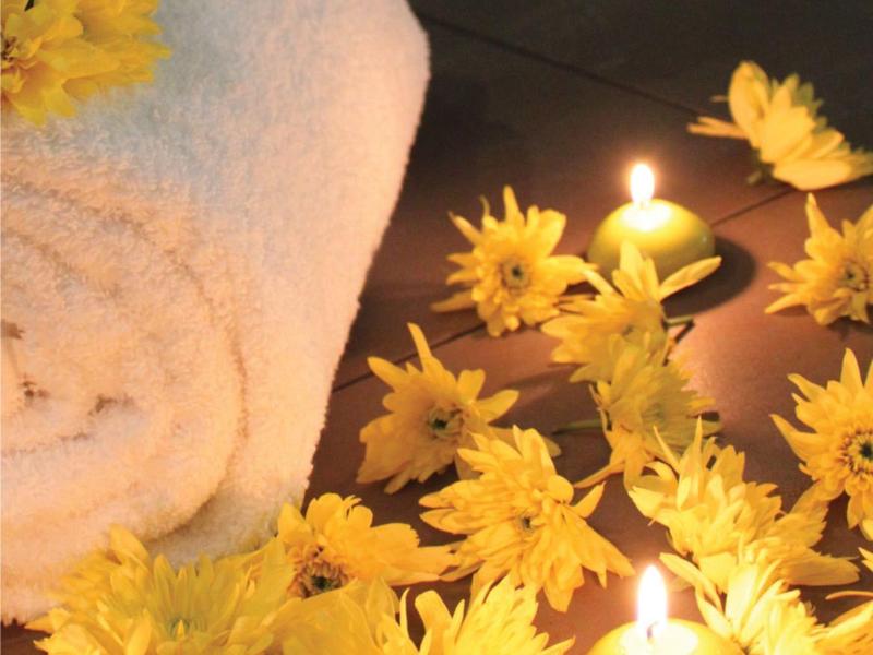 Toallas blancas con flores amarillas y velas encendidas para un ambiente relajante.