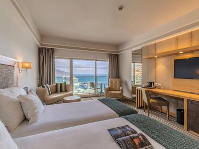 Helles Hotelzimmer mit zwei Betten, Meerblick und modernem Holzmöbel-Interieur.