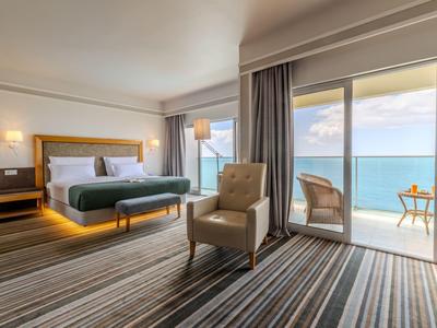 Modern eingerichtetes Hotelzimmer mit Meerblick und Balkon bei Tageslicht.