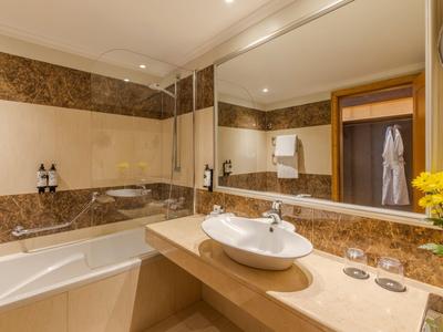 Modernes Hotelbadezimmer mit großer Badewanne, großem Spiegel und eleganter Waschbeckenanlage.