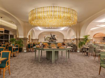 Eleganter Hotel-Speisesaal mit rundem Buffet und goldenem Kronleuchter.