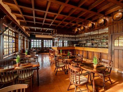 Helles, holzgetäfeltes Restaurant mit Tischen, Stühlen und langem Bartresen.