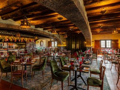 Rustikale Hotelbar mit Holzbalkendecke, vielen Tischen und Sitzplätzen in warmem Licht.