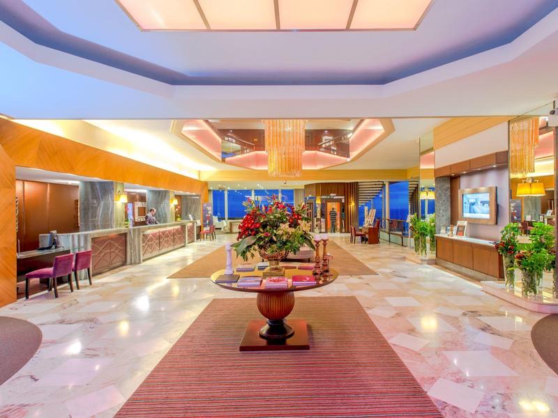 Helle Empfangshalle mit blühendem Blumenarrangement auf rundem Holztisch und Marmorfußboden.