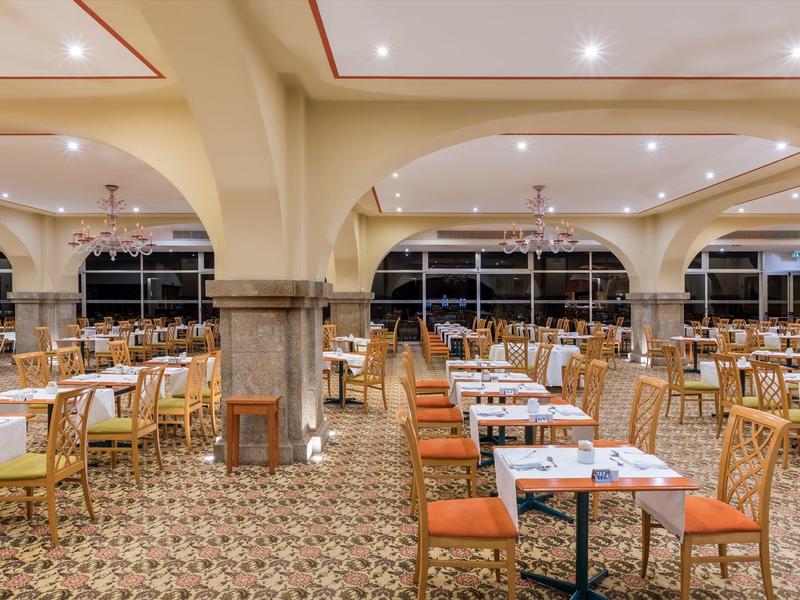 Großer, heller Speisesaal mit vielen Bestuhlungstischen und gemustertem Boden in warmen Farben.