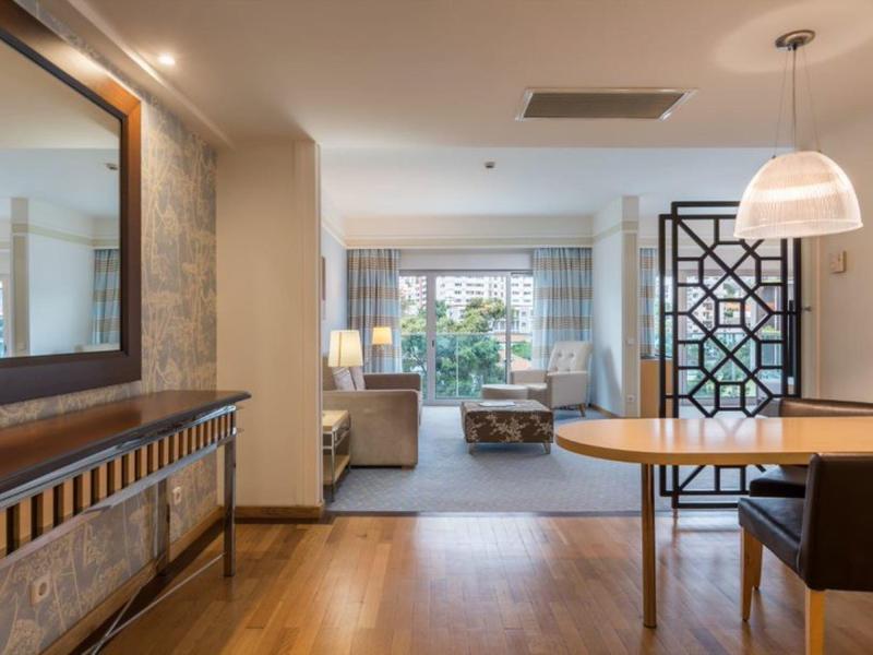 Moderner Wohnraum mit Holzboden, großem Spiegel, Glaswand und offenem Ess- und Wohnzimmerbereich.