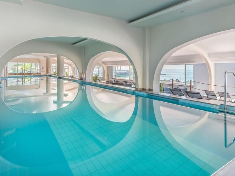 Helles Hallenbad mit großen runden Fenstern und Blick auf die Außenlandschaft.