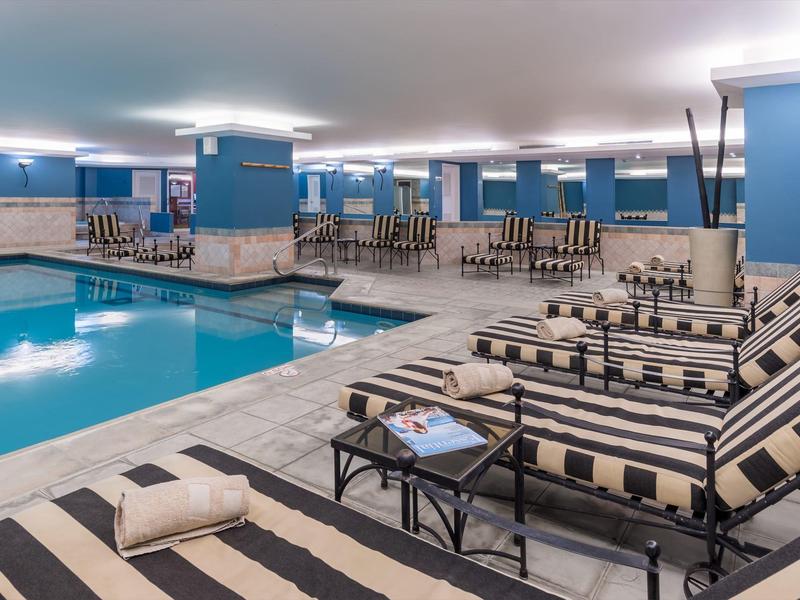 Innenpool mit blau-weiß gestreiften Liegestühlen, Säulen und einem gemütlichen Ambiente.