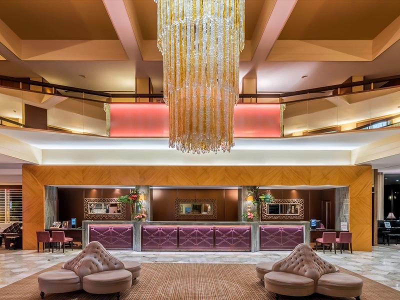 Eleganter Hotel-Lobbybereich mit großem Kronleuchter, Sitzgruppen und heller, moderner Einrichtung.