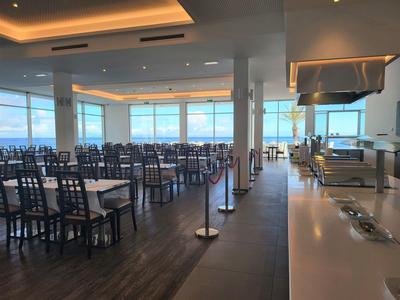 Heller, moderner Speisesaal mit Reihen von Tischen und Stühlen und großer Fensterfront