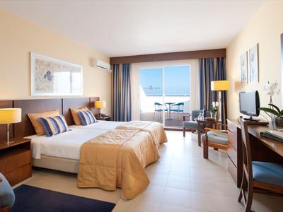 Leerer Außenbereich eines Restaurants mit weißen Tischen und Stühlen, Palmen und Meer im Hintergrund