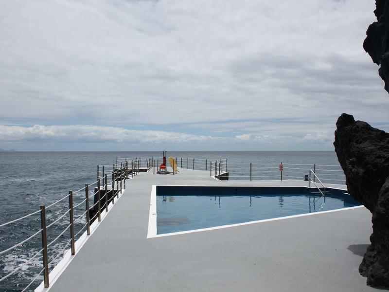 Schwimmbad auf einer Plattform mit Blick auf das Meer unter bewölktem Himmel