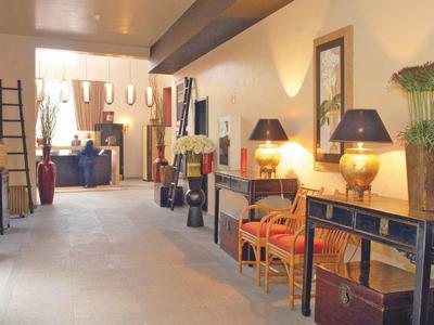 Světelná hotelová chodba s stoly, židlemi, lampami a dekoracemi podél zdí.