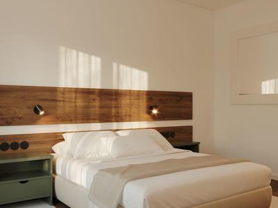 Moderně zařízený hotelový pokoj s velkou postelí, dřevěným čelem a nočními stolky