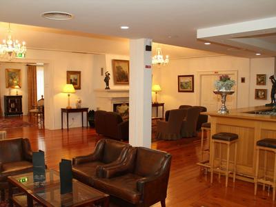 Gezellige hotel lounge met leren fauteuils, houten vloer en bar.