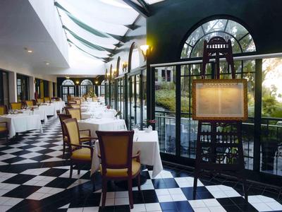 Restaurant élégant avec sol en carreaux noir et blanc et tables blanches dressées près de la fenêtre.