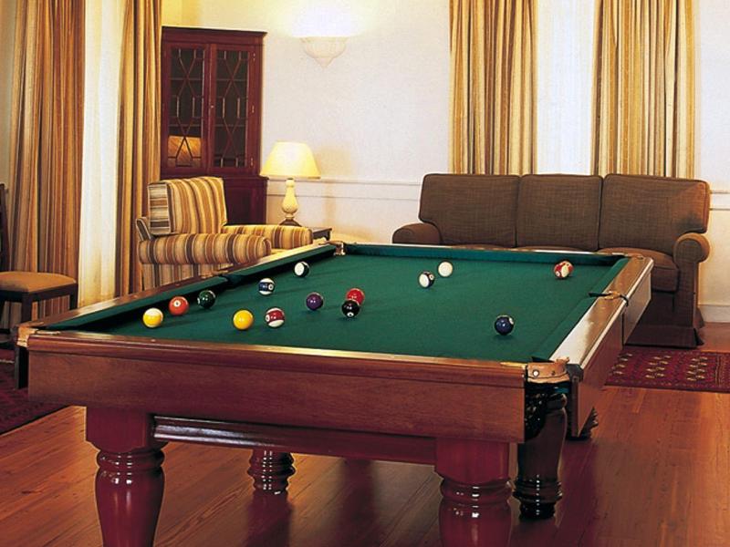 Gezellige woonkamer met een pooltafel, bruine sofa's en warm licht.