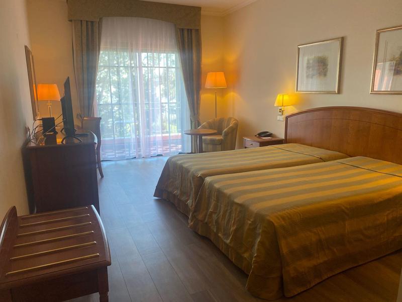 Gezellige hotelkamer met tweepersoonsbed, gordijnen en houten vloer.