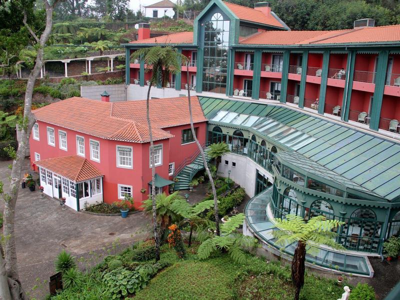 Hotel met rode en groene gebouwgedeelten omgeven door weelderige groene begroeiing.