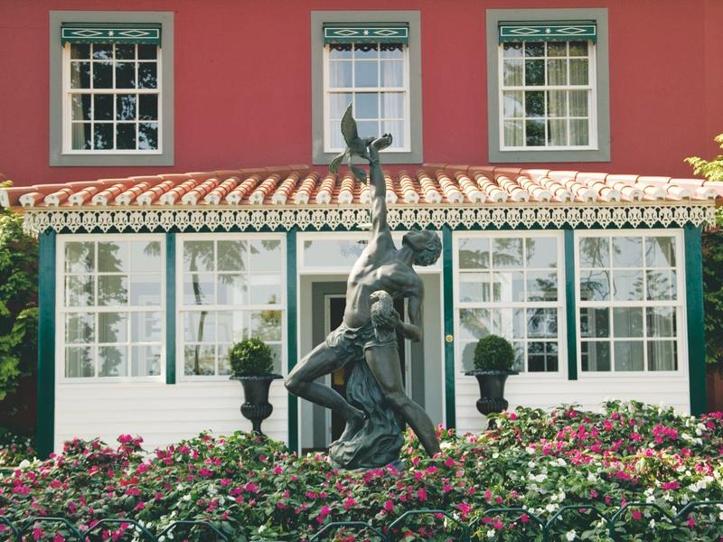 Bronzen beeld voor een traditioneel huis met rode muren en witte ramen.