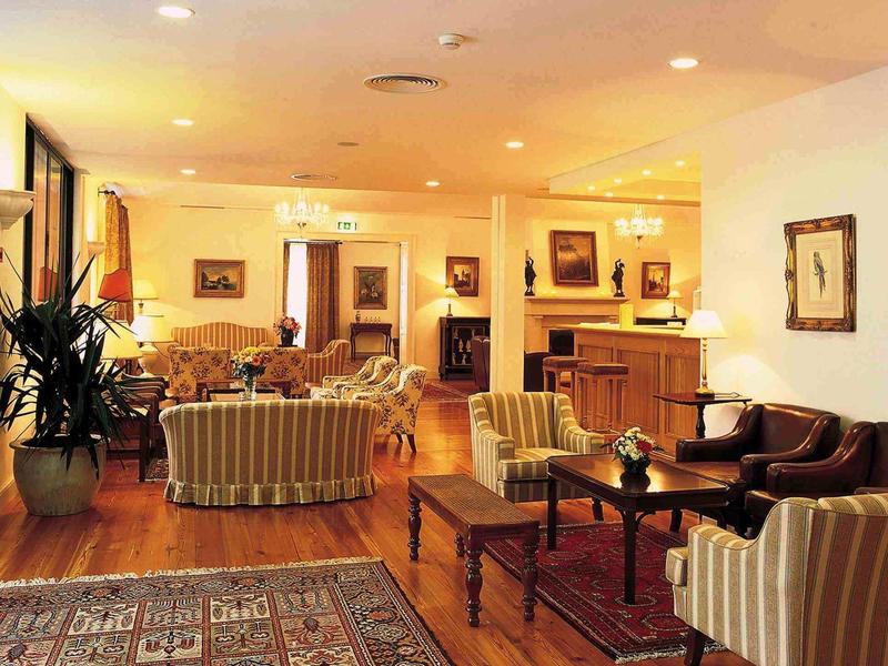 Lichte hotelkamer met klassieke zitgroepen, tapijten en warme houten vloeren