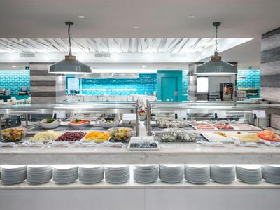 Buffet mit vielfältigen Speisen in hellem, modernem Restaurant mit Holz- und Metallakzenten.