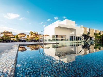 Moderner Gebäudekomplex mit glattem Pool, klaren blauen Fliesen und sonnigem Himmel.