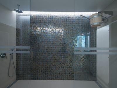 Moderne Dusche mit Glaswand, Regendusche und Schlauchbrause, heller Fliesenboden und Wand.
