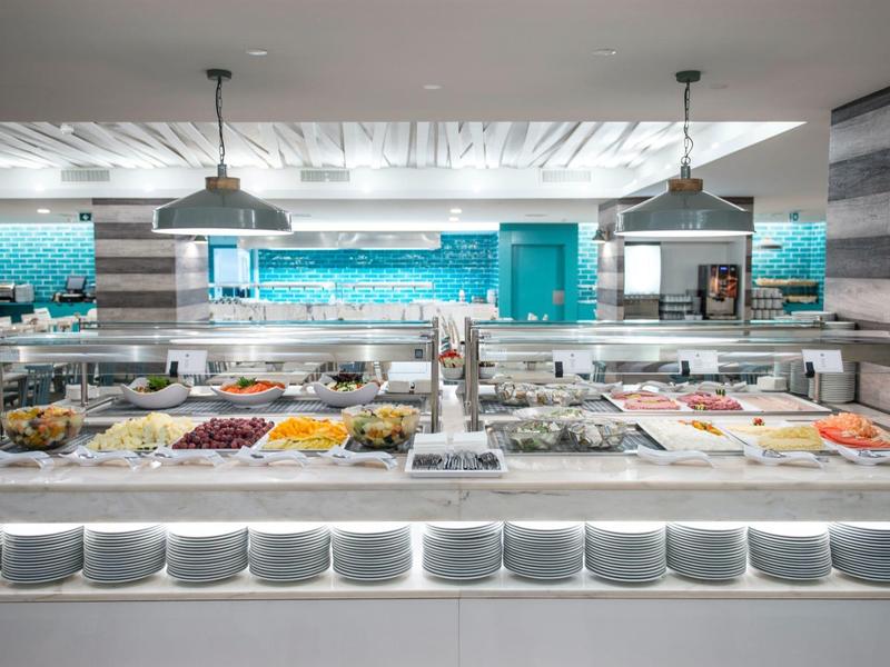 Moderní bufet s různými pokrmy v nádobách v světlé restauraci.