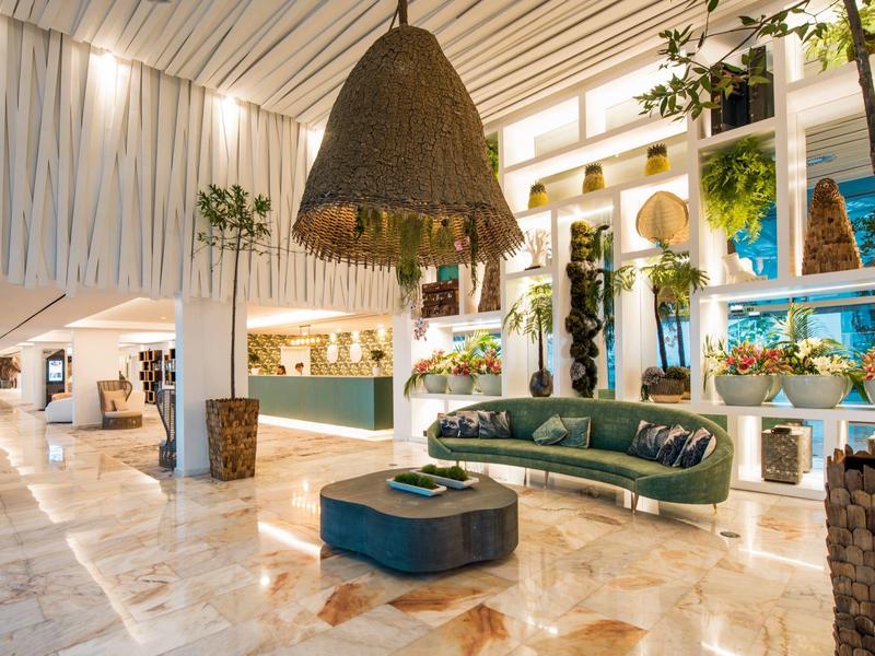 Elegantní hotelové lobby se zelenou pohovkou, teplým osvětlením a přírodními dekoracemi.