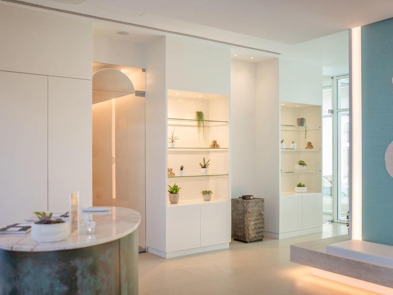 Moderní interiér hotelu s bílými zdmi, kulatým pultem a světlým výstavním prostorem.