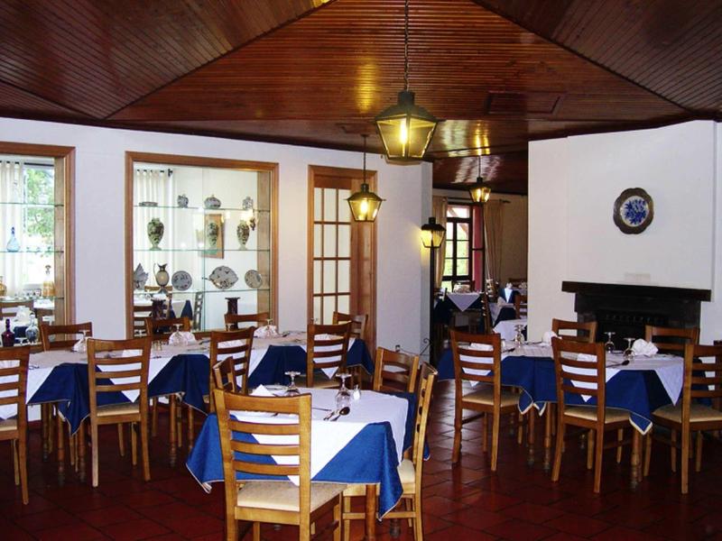 Interiér útulné restaurace s dřevěným nábytkem a modrými ubrusy.